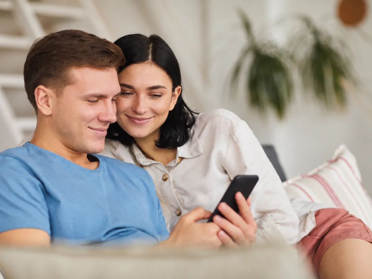 Coppia rilassata sul divano che controlla lo smartphone