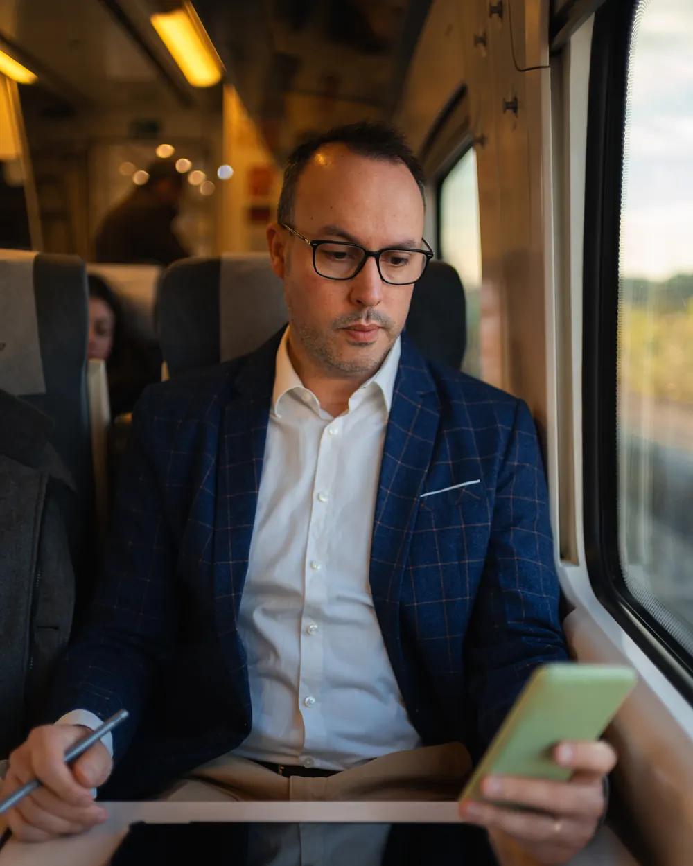 Uomo in treno che guarda lo smartphone lontano da casa